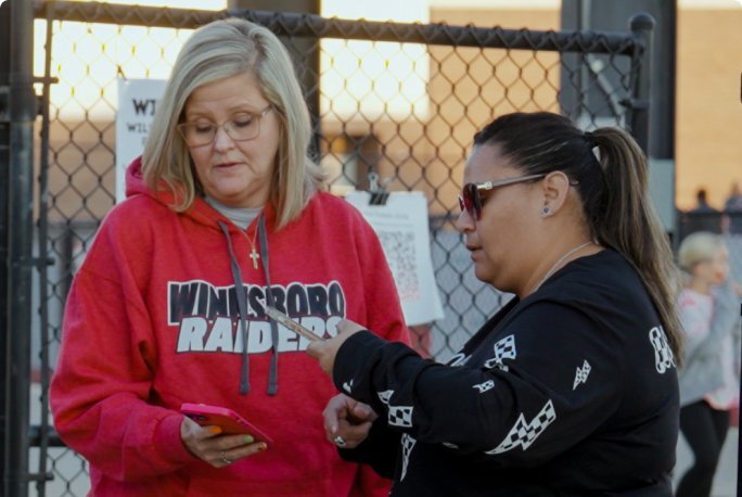 A ticketing agent scanning a digital ticket on a fan's phone.