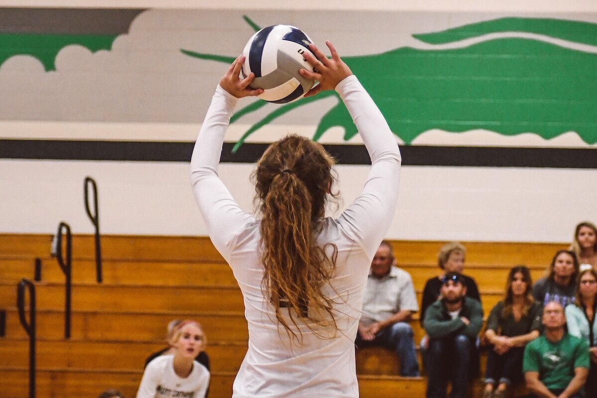 Volleyball setter setting the ball during a match inside a gymnasiam.