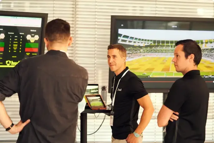 Coaches and analyists reviewing sports footage and reports on multiple large TVs.