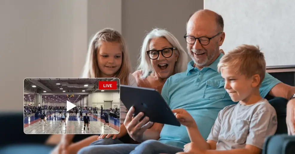 Photoillustration of an older couple sitting on a couch with two you children. They are holding an iPad that is streaming a volleyball match and cheering for their team.